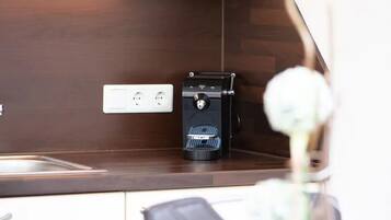 A modern kitchen with a built-in microwave, a coffee machine, and a wooden countertop.