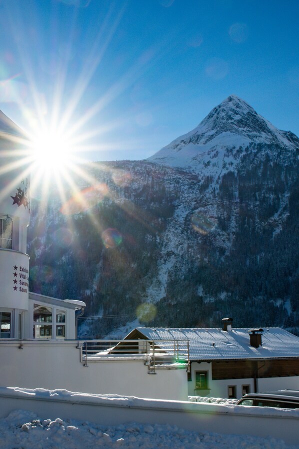 A snow-covered mountain with a bright sun in the background.