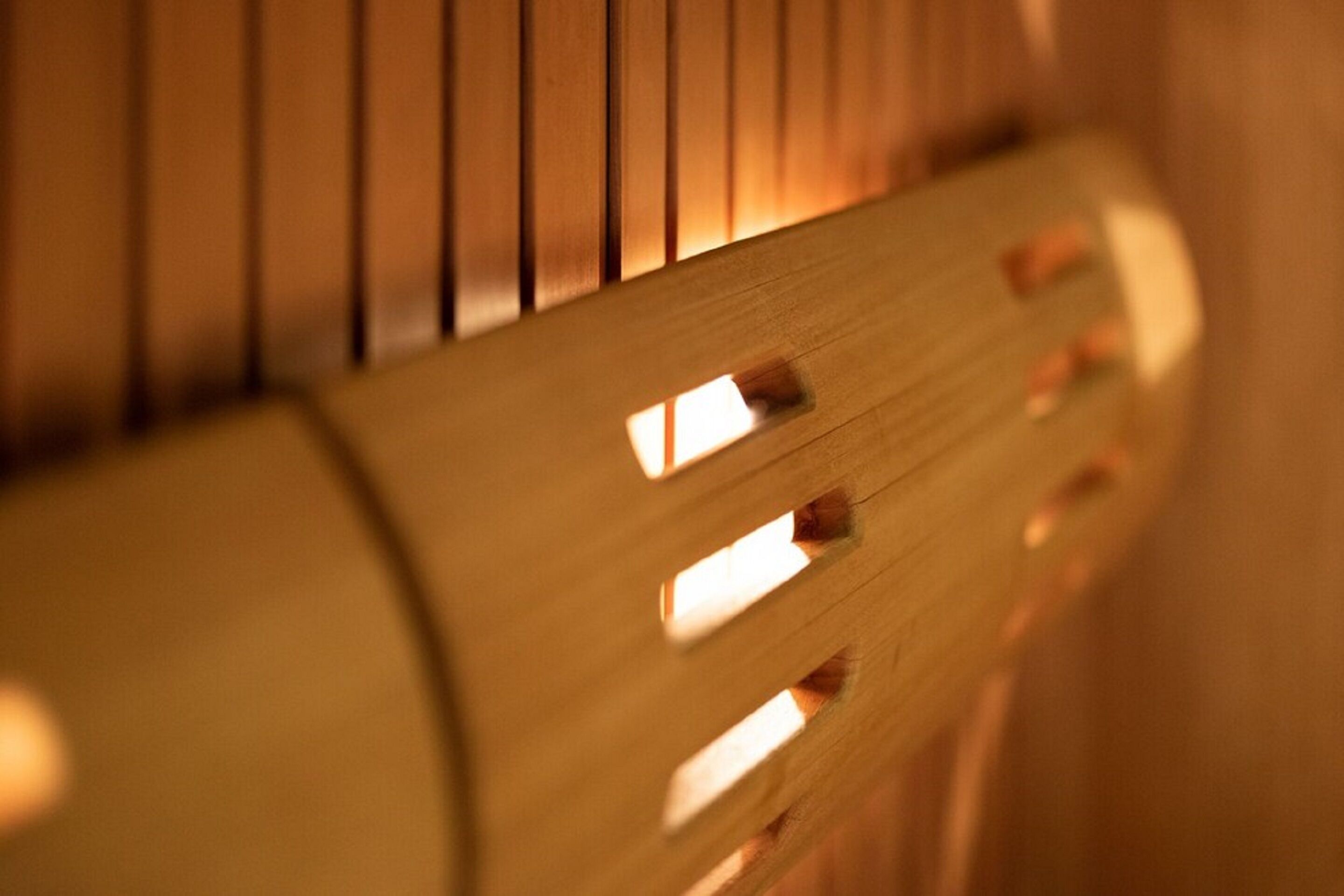 A close-up of a wooden chair with slatted backrests and a cylindrical wooden frame.