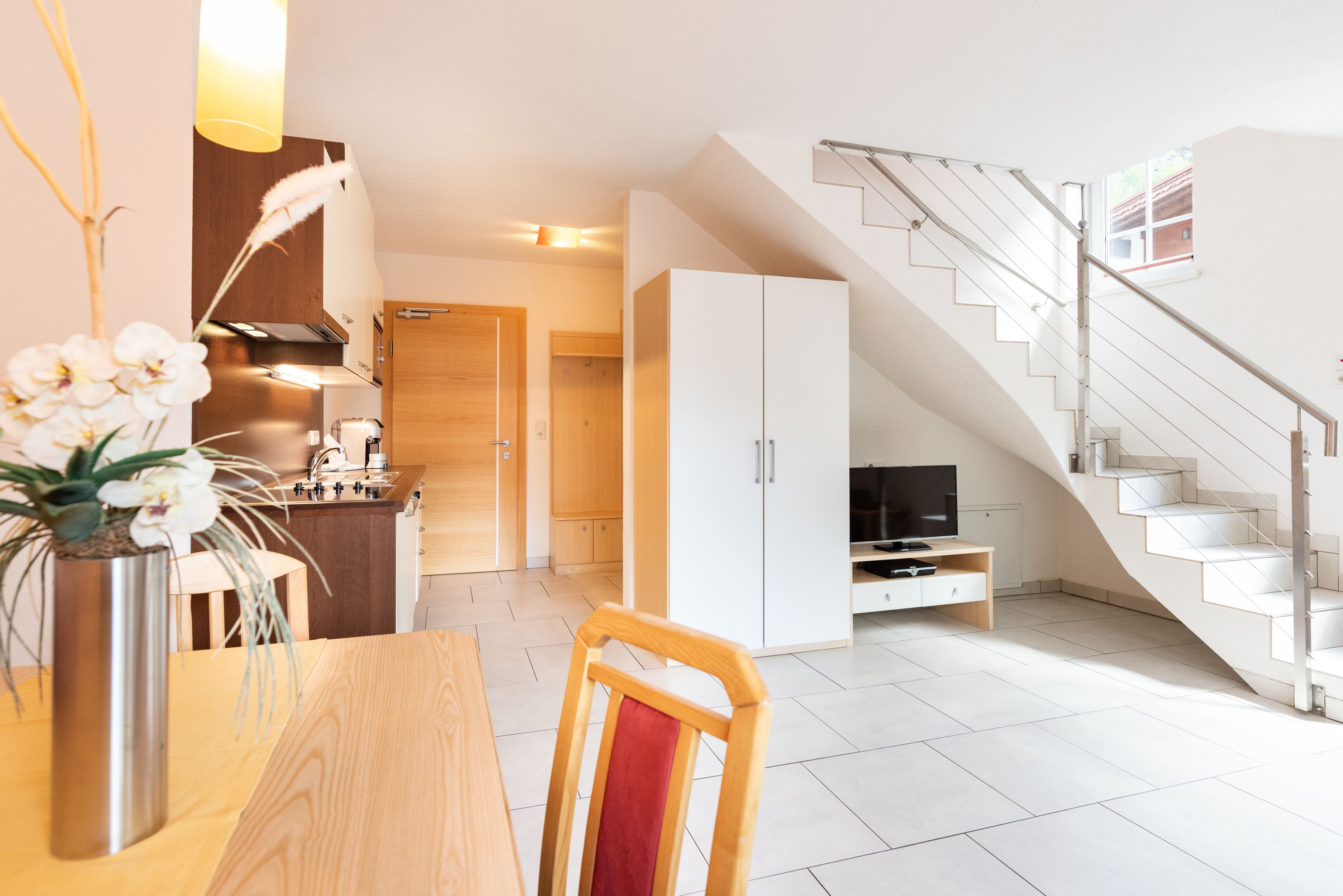 Un apartamento moderno con cocina, comedor y una escalera que lleva a un piso superior.