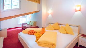 Une chambre à coucher avec un lit, des oreillers, une table de chevet, un canapé rouge et une fenêtre.