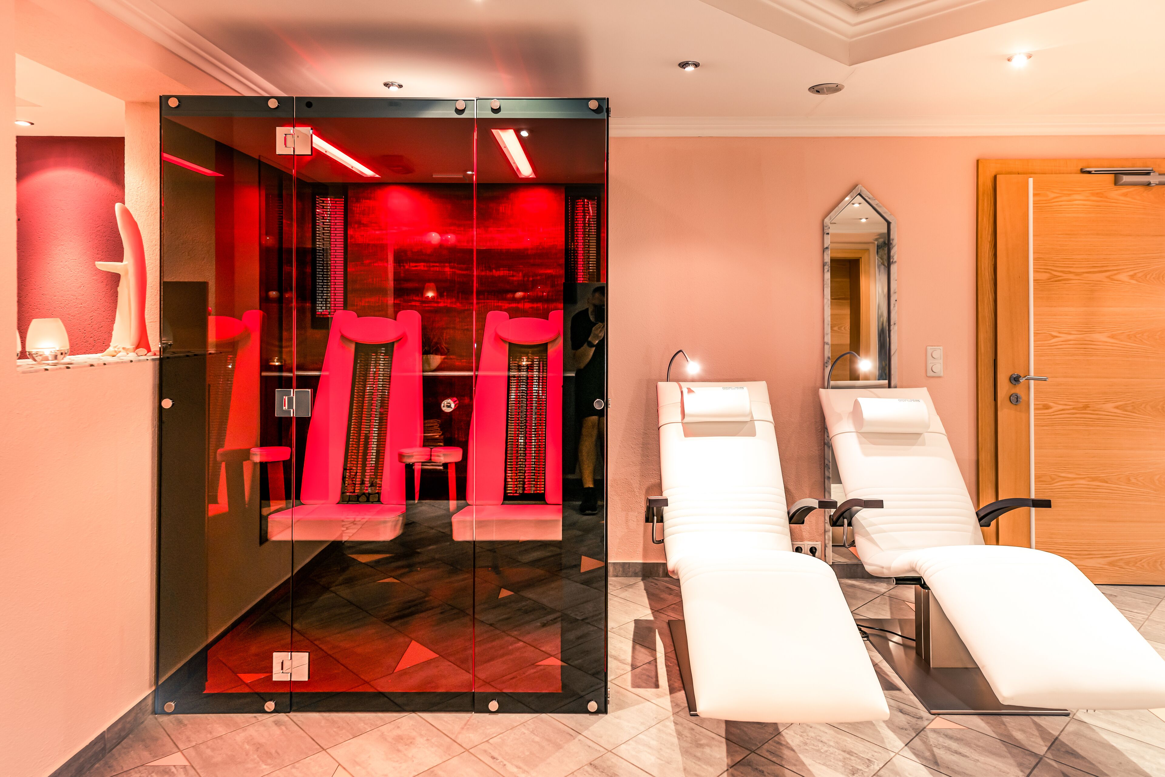 Une salle de spa moderne avec une paroi en verre, deux fauteuils inclinables et une porte en bois.