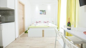 A modern bedroom with a bed, bedside table, and a TV mounted on the wall. - Apartments Gabrieri - Studio with Sea View (2 Adults + 1 Child) (2) (Dubrovnik)