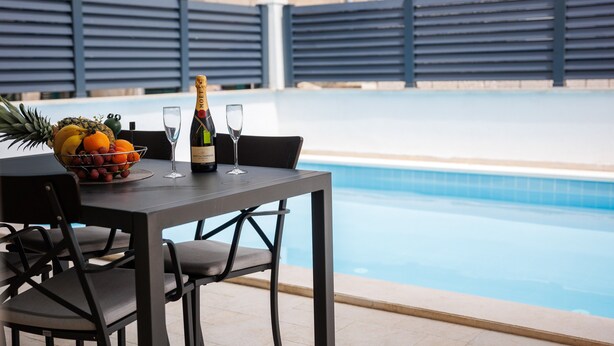 A poolside table with a fruit bowl, wine glasses, and a bottle of champagne. - Apartments Gabrieri - Studio with Sea View (2 Adults + 1 Child) (2) (Dubrovnik)
