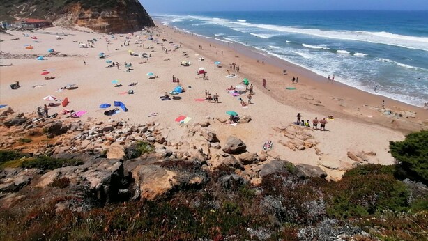 A beach with rocky foreground, a cliff, and the ocean.