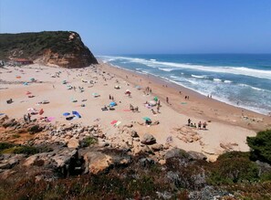 Ein Strand mit felsigem Vordergrund, einer Klippe und dem Ozean.