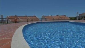 A swimming pool with a tiled deck, a lifebuoy, and a fence.
