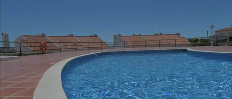 Uma piscina com deck revestido, uma boia e uma cerca.