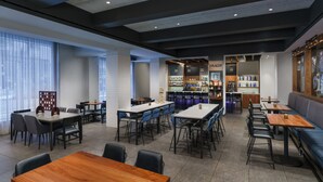 Ein modernes Restaurant mit verschiedenen Sitzbereichen, darunter Tische, Boxsitzgelegenheiten und eine Bar mit Flaschenregalen.