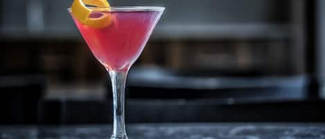 A martini glass with a lemon garnish on a reflective surface.