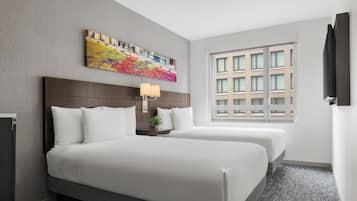 Una habitación de hotel con dos camas, un ventanal grande y una obra de arte colorida en la pared.