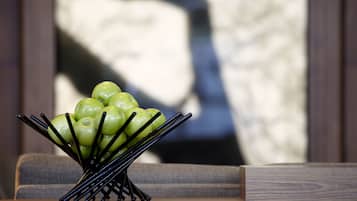 Una mesa de madera con un frutero negro que contiene manzanas verdes.