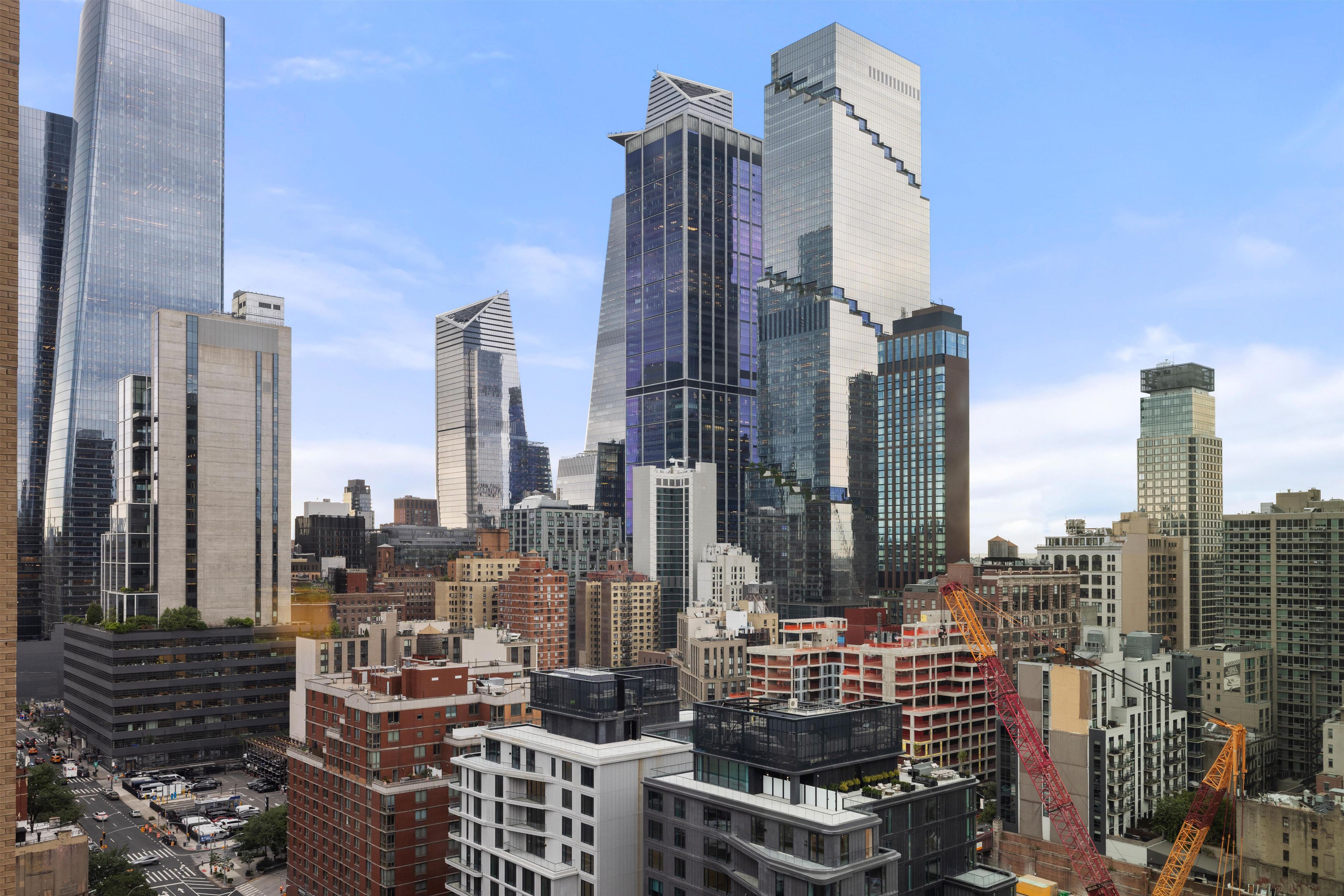 A cityscape with modern high-rise buildings, a construction crane, and a busy street below.