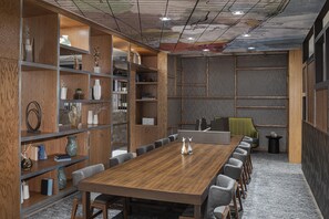 Ein Konferenzraum mit einem langen Holztisch, grauen Stühlen und integrierten Holzbögen mit verschiedenen Dekorationselementen.