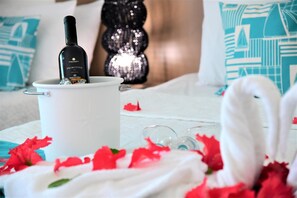 A bed with a bottle of wine, glasses, and red flowers. - Villa Caracol (Ipojuca)