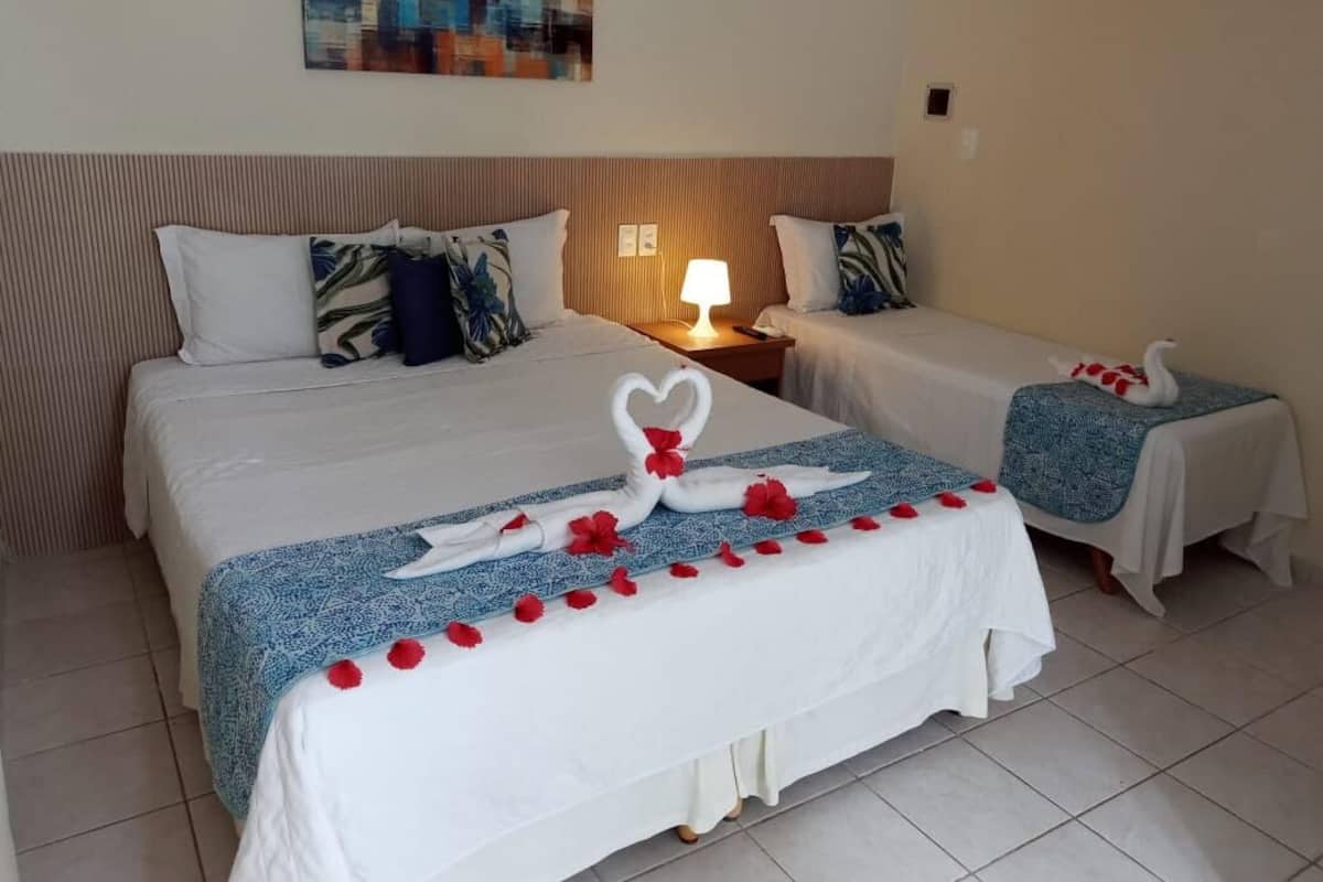 A hotel room with two beds, each with a blue and white patterned bedspread, and a decorative swan centerpiece.