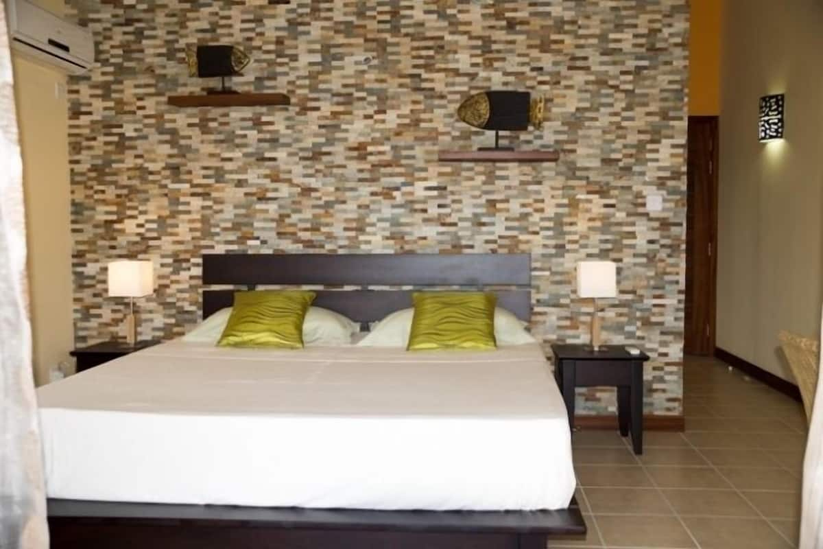 A bedroom with a bed, two nightstands, and a wall with a mosaic pattern.