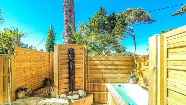 Eine Holzterrasse mit einer Steinsitzbank, einem kleinen Pool und einem Holenzaun.