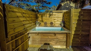 Ein Spa-Bereich aus Holz mit Whirlpool, Steintreppe und Holzzaun.