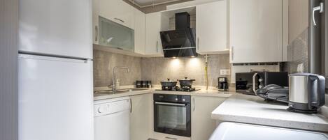 A modern kitchen with white cabinetry, a built-in oven, a microwave, and a kettle.