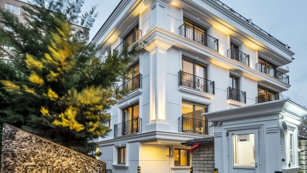 A multi-story hotel with a classic architectural design, featuring balconies and a well-lit entrance. - Ciragan Suites Bosphorus (Istanbul)