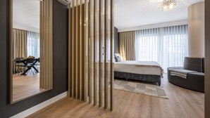 A modern hotel room with a large bed, a sofa, a dining area, and a large mirror. - Ciragan Suites Bosphorus (Istanbul)