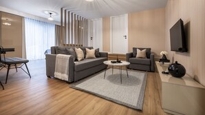 A modern living room with a sectional sofa, a round coffee table, and a flat-screen TV mounted on the wall. - Ciragan Suites Bosphorus (Istanbul)