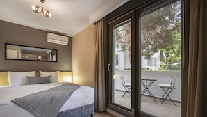 A modern hotel room with a large bed, a sliding glass door to an outdoor balcony, and a ceiling light fixture. - Ciragan Suites Bosphorus (Istanbul)