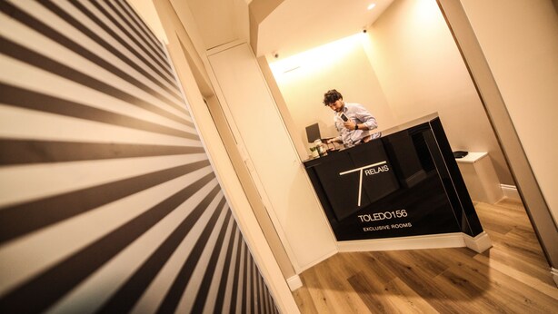 Un espace d’accueil d’hôtel au design moderne, comprenant un comptoir de réception portant les inscriptions « RELAIS » et « TLED0156 CHAMBRES DE LUXE ».