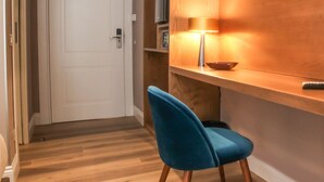 Une chambre moderne avec un mur d’accent en bois, un téléviseur fixé au mur et un fauteuil bleu.