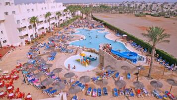 Relax by the resort's central pool, surrounded by smaller pools and sun loungers, with palm trees and city views.