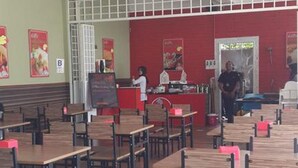 A spacious restaurant with multiple tables and chairs, ceiling fans, and a red counter area.