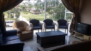 A living room with a sofa, two armchairs, a coffee table, and a TV.