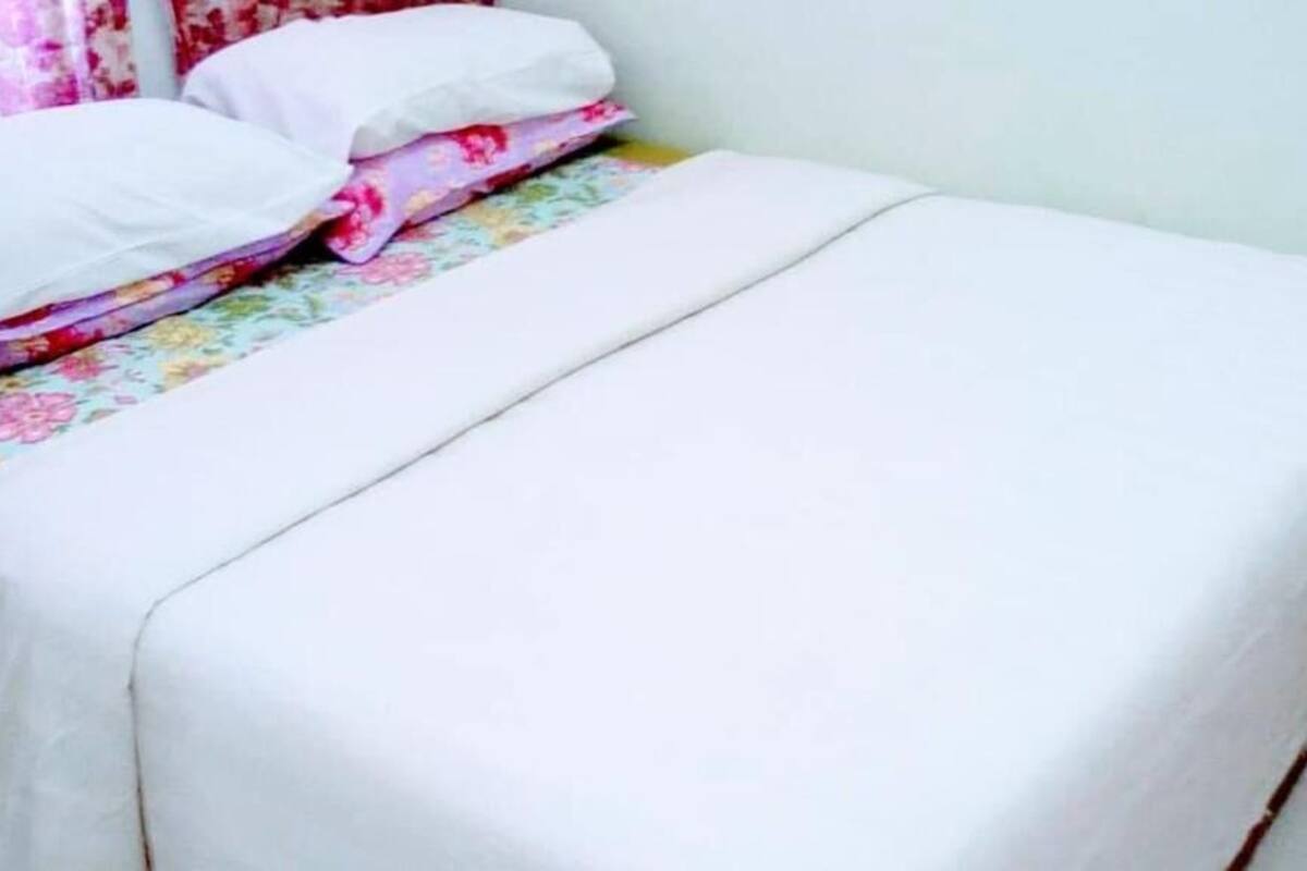 Un lit avec un matelas blanc et une literie à motifs floraux.
