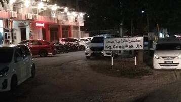 A parking area with several cars and a sign indicating "Kg. Gong Pak Jin".
