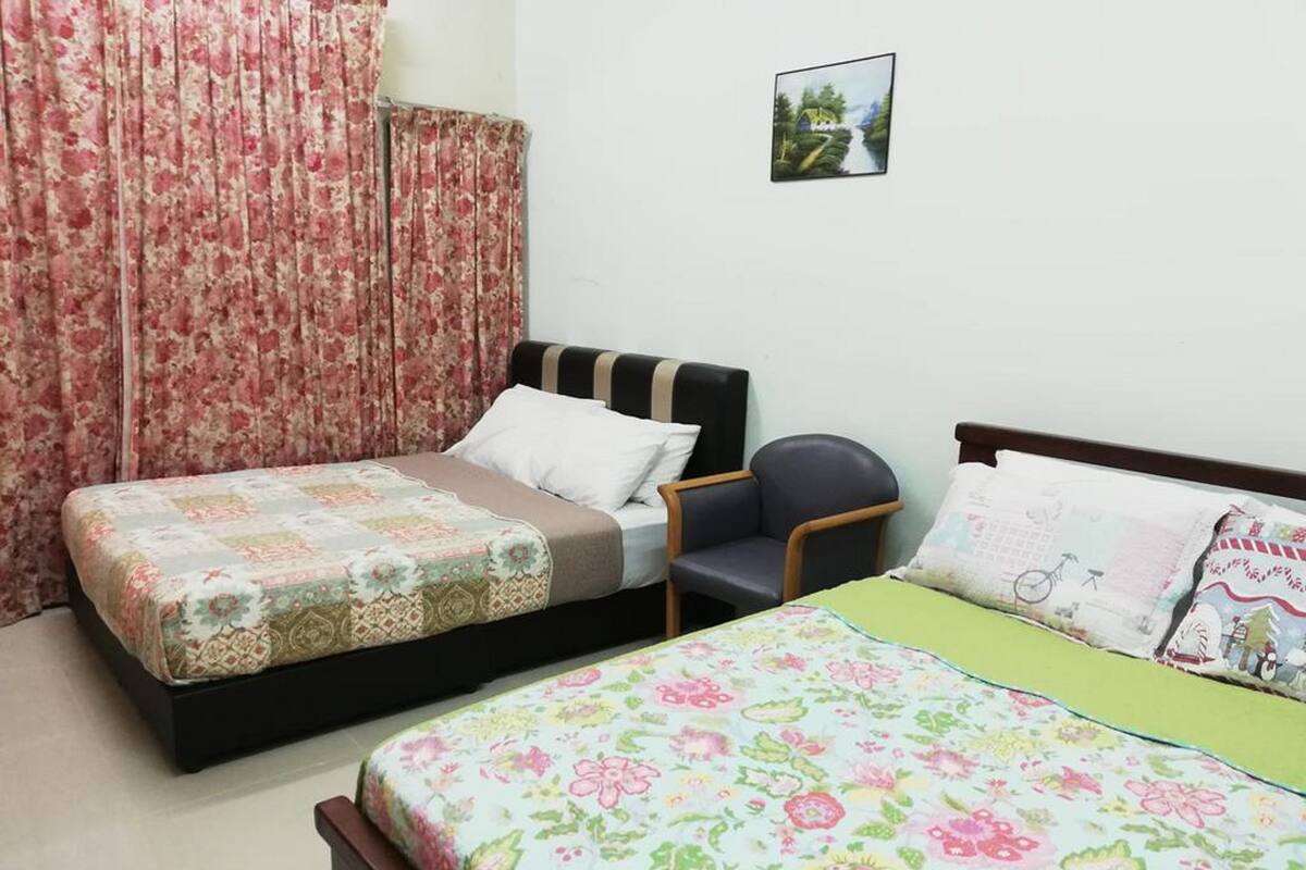 Une chambre avec deux lits, une chaise et un tableau au mur.