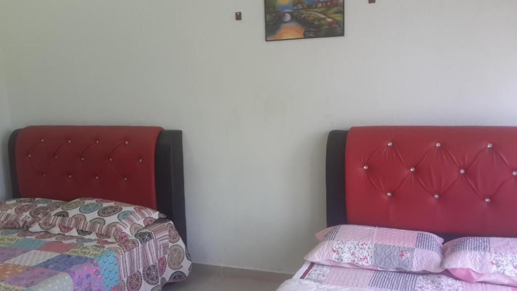 Two beds with red headboards in a room with plain walls and a single painting on the upper wall.