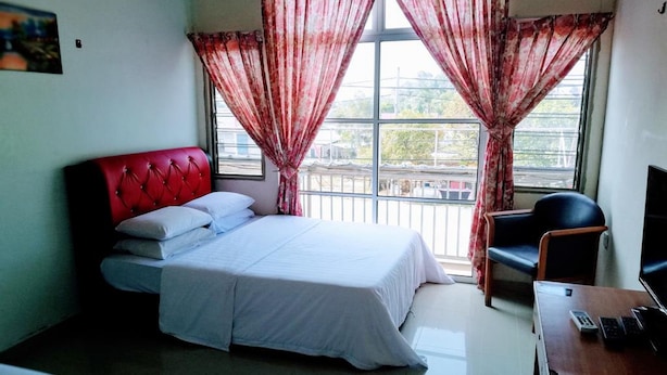 A hotel room with a bed, a desk with a computer, a chair, and a TV.