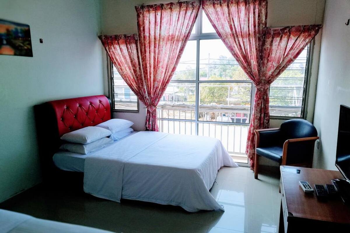 Une chambre d’hôtel avec un lit, un bureau avec un ordinateur, une chaise et un téléviseur.