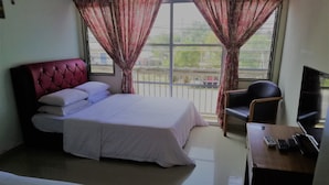 A hotel room with a bed, a desk with a laptop, a chair, and a TV.