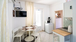 Una cucina compatta con zona pranzo, una TV a parete e un forno a microonde sul ripiano.