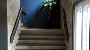 A staircase with wooden steps leading to a landing, flanked by a blue wall and a potted plant. - Torrent River Inn (Hawke's Bay)