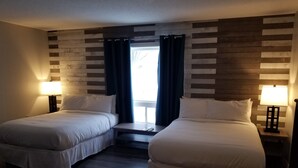 A hotel room with two single beds, a small table, and a window with curtains. - Torrent River Inn (Hawke's Bay)