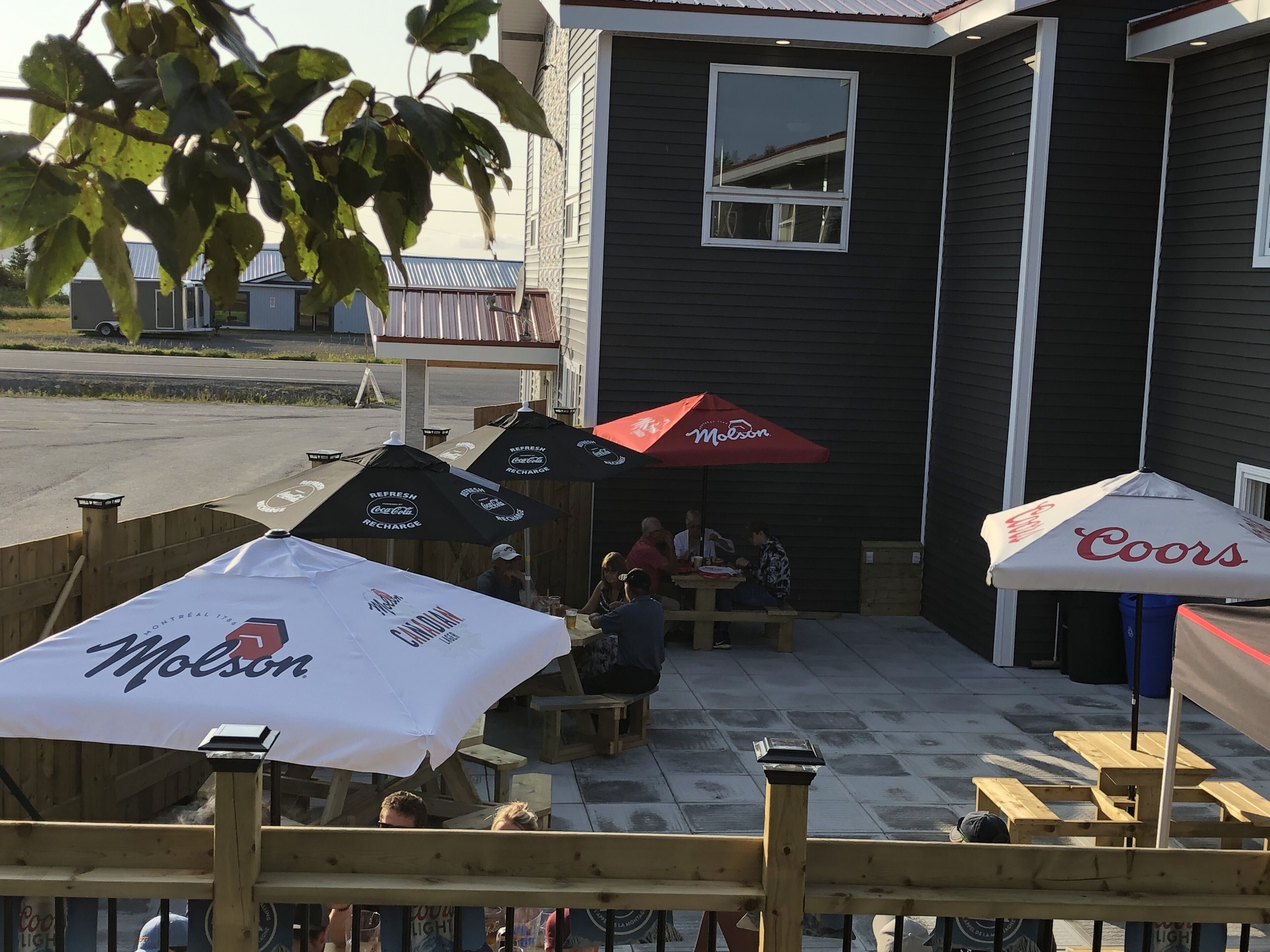 An outdoor seating area with tables and umbrellas branded with Molson and Coors.