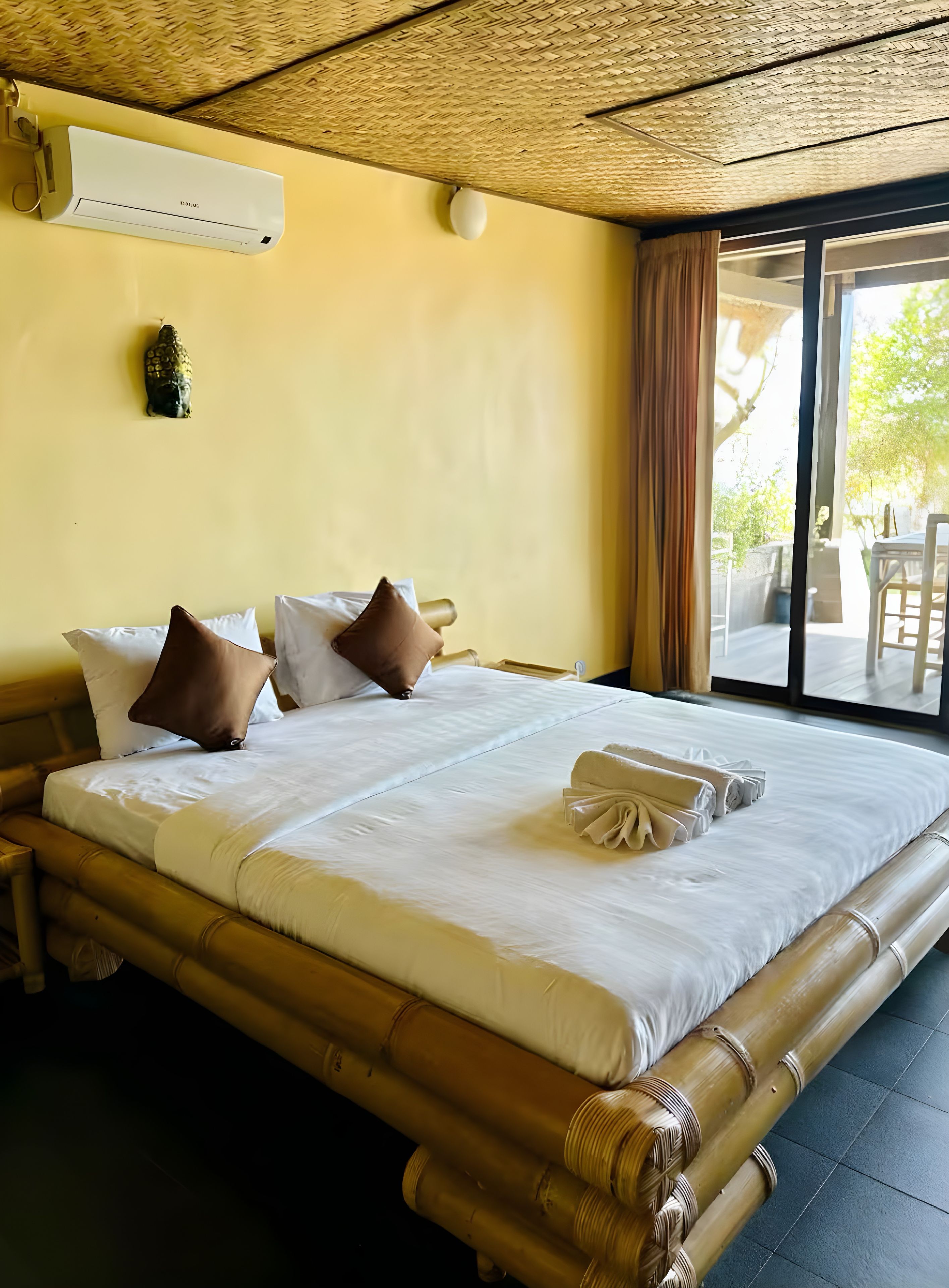 A hotel room with a large bed, a ceiling fan, and a view of the outdoors.