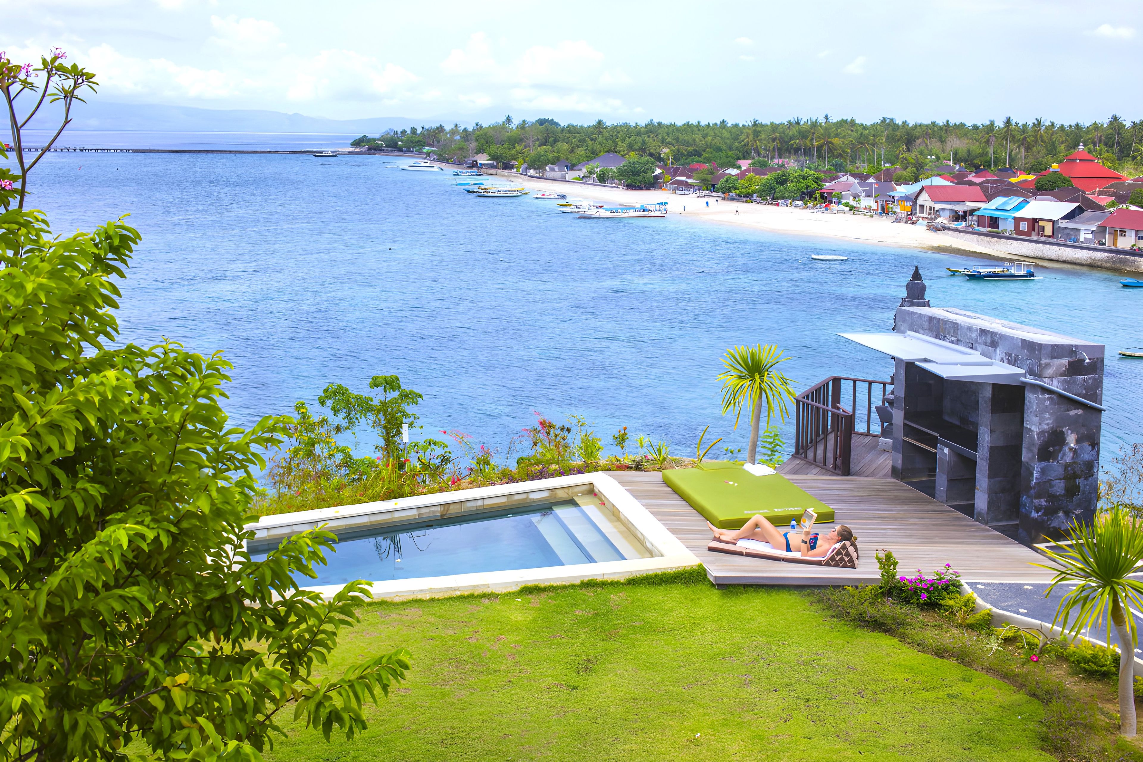 A pool area with a view of the ocean and a beach.