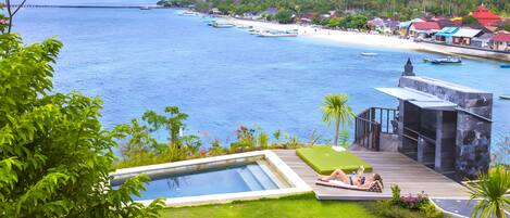 A pool area with a view of the ocean and a beach.