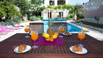 Enjoy a meal in a serene outdoor setting with a pool view.