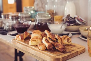 A wooden board with pastries and jars of preserves on a table.