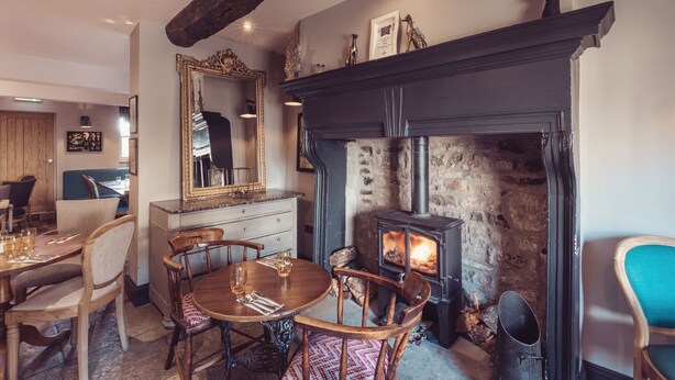 A cozy dining area with a fireplace, wooden furniture, and a stone wall. - The New Inn - Yealand (Carnforth)